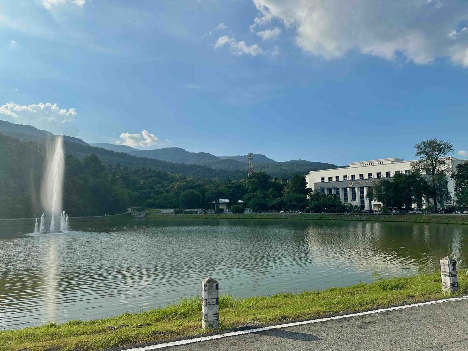 Ang Kaew reservoir in Chiang Mai, with its fountain and the green Doi Suthep hills behind on a clear day