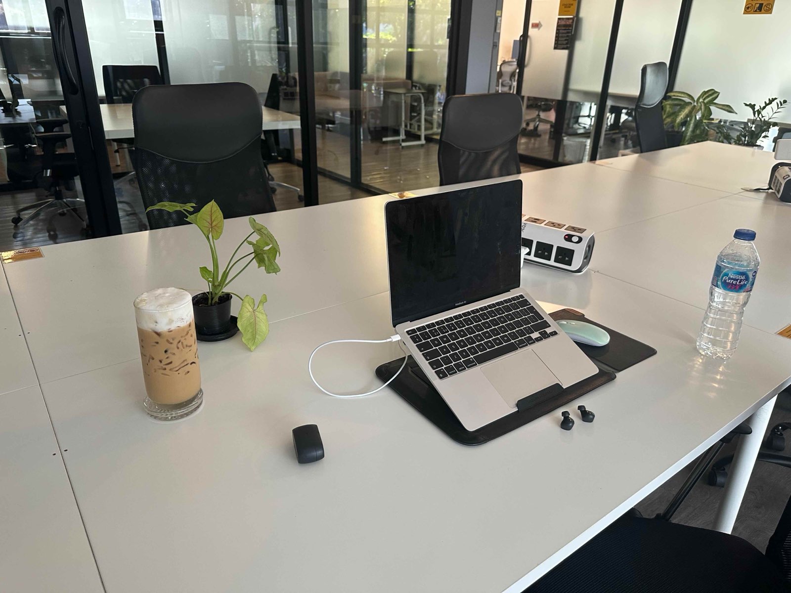Laptop, iced coffee and a pot plant on a shared desk at Yellow Coworking in Chiang Mai